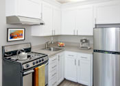 Thumbnail 2 of 28 - A kitchen with white cabinets and a stainless steel refrigerator.