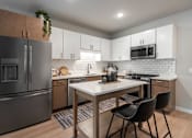 Thumbnail 60 of 68 - A modern kitchen with a white countertop and a black chair.