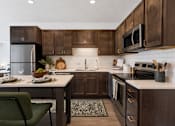 Thumbnail 5 of 35 - A modern kitchen with dark wood cabinets and a green chair.