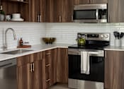 Thumbnail 3 of 34 - A modern kitchen with wooden cabinets and stainless steel appliances.