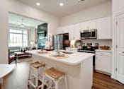 Thumbnail 2 of 27 - A kitchen with white cabinets and a large island with bar stools.