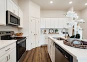 Thumbnail 21 of 27 - A kitchen with white cabinets and a black microwave.