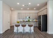Thumbnail 12 of 31 - a kitchen with a island with three stools and a black refrigerator