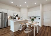 Thumbnail 22 of 27 - A kitchen with white cabinets and a wooden table.