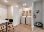 Thumbnail 58 of 68 - A laundry room with a washer and dryer, a table, chairs, and a basket.