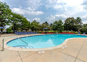 Thumbnail 13 of 19 - A large swimming pool surrounded by trees and a clear sky.