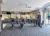 Thumbnail 12 of 19 - A gym with a variety of equipment including treadmills, stationary bikes, and weight machines.