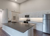 Thumbnail 1 of 19 - A modern kitchen with a large island and stainless steel appliances.