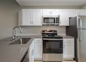 Thumbnail 8 of 19 - A modern kitchen with a stove, sink, and refrigerator.