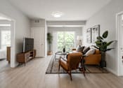 Thumbnail 65 of 68 - A living room with a sofa, a chair, and a television.