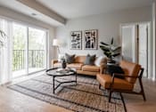 Thumbnail 55 of 68 - A living room with a brown leather chair and a black coffee table.