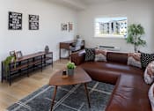 Thumbnail 11 of 27 - A living room with a brown leather couch and a wooden coffee table at The Arvon, Vancouver