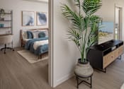 Thumbnail 13 of 34 - A bedroom with a bed, a plant, and a painting on the wall.
