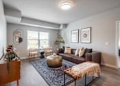Thumbnail 1 of 35 - A living room with a brown leather couch, a round coffee table, and a large window.