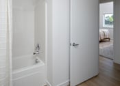 Thumbnail 8 of 27 - A white bathroom with a tub and a door.