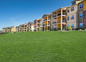 Thumbnail 25 of 26 - Apartment complex with green grass in front.