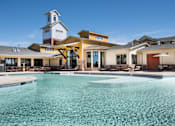 Thumbnail 26 of 26 - A large swimming pool in front of a building with a clock tower.