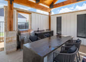 Thumbnail 4 of 28 - an outdoor kitchen with a table and chairs and a grill
