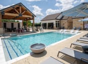 Thumbnail 3 of 28 - a swimming pool with lounge chairs and a building with a pavilion