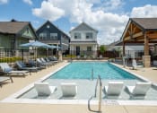 Thumbnail 1 of 28 - a swimming pool with chairs and umbrellas in front of houses