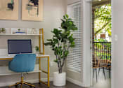 Thumbnail 4 of 34 - A room with a desk, chair, and a potted plant.