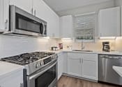 Thumbnail 19 of 21 - a kitchen with white cabinets and stainless steel appliances