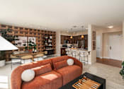 Thumbnail 3 of 28 - A living room with a couch, a coffee table, and a kitchen area in the background.