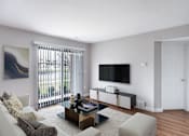 Thumbnail 1 of 22 - A living room with a white couch, a coffee table, and a painting on the wall.