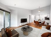 Thumbnail 7 of 22 - A modern living room with a flat screen TV, a glass table, and a white couch.