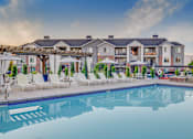 Thumbnail 28 of 34 - a swimming pool with chairs and umbrellas and a building in the background