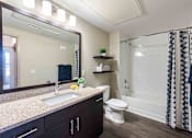 Thumbnail 40 of 41 - A bathroom with a sink, toilet, and a shower with a black and white curtain.