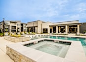 Thumbnail 19 of 26 - A swimming pool in front of a building with a stone wall.