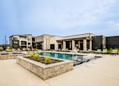 Thumbnail 25 of 26 - A pool surrounded by a concrete patio and a stone planter.