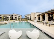 Thumbnail 2 of 26 - Two white chairs are placed in the middle of a pool.