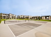 Thumbnail 18 of 26 - A tennis court is surrounded by apartment buildings.