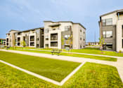 Thumbnail 23 of 26 - Apartment complex with a green lawn in front.