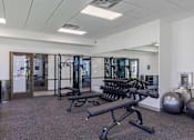 Thumbnail 14 of 26 - A gym with a variety of equipment including a leg press machine, a rowing machine, and a weight bench.