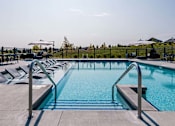 Thumbnail 16 of 16 - Pool with lounge chairs at Velo Village Apartments near Whitnall Park.
