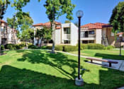 Thumbnail 5 of 26 - A sunny day at a park with a bench and a lamp post at The Casas Apartments, San Diego, CA, 92126
