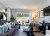 Thumbnail 14 of 26 - A modern living room with a grey couch and a coffee table at The Casas Apartments, San Diego, California