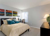 Thumbnail 16 of 26 - A bedroom with a bed, nightstand, lamp, and a plant at The Casas Apartments, San Diego, CA