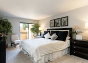 Thumbnail 20 of 26 - A bedroom with a large bed, a chair, and a potted plant at The Casas Apartments, San Diego, 92126