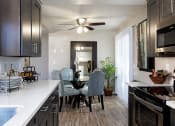 Thumbnail 21 of 26 - A kitchen with a dining table and chairs at The Casas Apartments, San Diego, CA