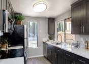Thumbnail 22 of 26 - A kitchen with black cabinets and a black fridge at The Casas Apartments, San Diego, CA, 92126