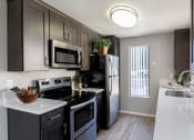 Thumbnail 3 of 26 - A modern kitchen with dark wood cabinets and stainless steel appliances at The Casas Apartments, California, 92126