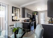 Thumbnail 23 of 26 - A modern kitchen with a glass table and chairs at The Casas Apartments, California