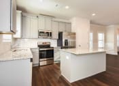 Thumbnail 40 of 60 - an open kitchen with white cabinets and a large island with granite countertops