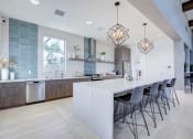 Thumbnail 38 of 47 - a large white kitchen with a bar and chairs