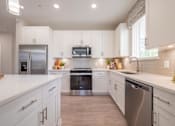 Thumbnail 10 of 31 - a large kitchen with white cabinets and stainless steel appliances