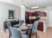 Thumbnail 2 of 32 - a dining room table with blue chairs and a kitchen with black appliances